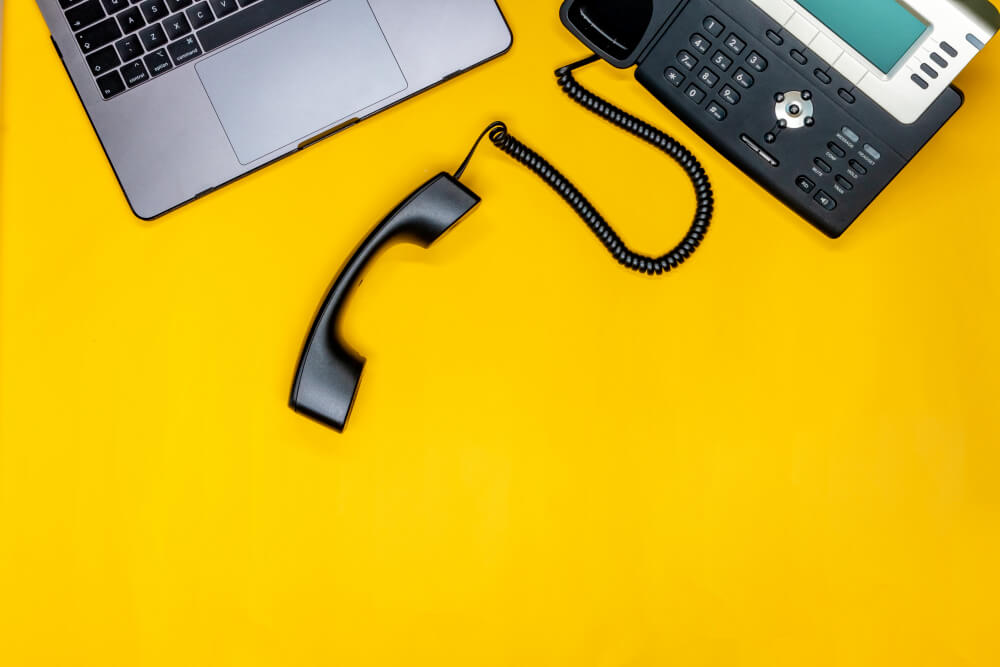 telephone-laptop-flat-lay-with-workspace-yellow-background